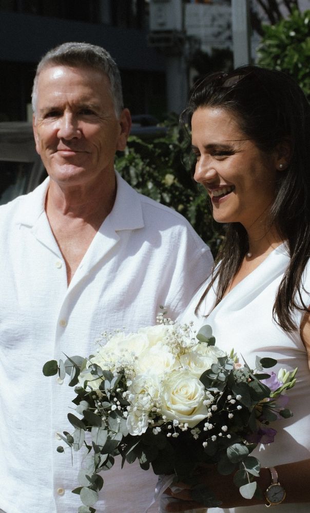 Pareja de novios sonriendo con ramo de rosas blancas